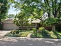 Charming ranch home featuring mature trees, beautiful landscaping, and a welcoming covered porch at 1985 Union St, Lakewood, CO 80215