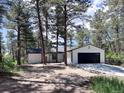 Well-maintained home showcasing a sleek garage door and a picturesque setting amongst towering pine trees at 14546 Pine View Rd, Larkspur, CO 80118