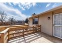 Outdoor deck, featuring a wooden railing, exterior door, and small yard at 8757 Estes Ct, Arvada, CO 80005