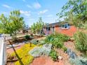 Well-manicured front yard showcasing colorful flower beds and a charming brick home with blue shutters at 4163 S Decatur St, Englewood, CO 80110