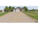 Wide driveway leading to a well-maintained home with a three-car garage and manicured lawn at 9576 E 147Th Pl, Brighton, CO 80602