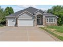 Charming home exterior featuring a stone facade, three-car garage, and well-maintained landscaping at 9576 E 147Th Pl, Brighton, CO 80602