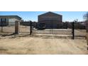 Iron-gated property entrance with decorative gate and large workshop building beyond the house at 15460 Casler Ave, Fort Lupton, CO 80136