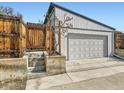 Detached garage with a gray door, adjacent to a wooden fence and steps leading to the yard at 170 W Midway Blvd, Broomfield, CO 80020