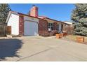 Brick home featuring an attached garage, mature trees, and a spacious driveway on a sunny day at 1755 S Yampa Way, Aurora, CO 80017