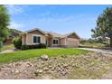 A single-story home with stone accents, lush lawn and attractive landscaping on a sunny day at 119 Lake Ave, Palmer Lake, CO 80133