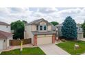 Inviting two-story house featuring a two-car garage, lush lawn, and mature trees at 5075 Weeping Willow Cir, Highlands Ranch, CO 80130