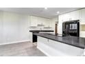 Bright kitchen featuring white cabinets, gray countertops, black refrigerator, and tiled flooring at 600 Manhattan Dr # 4C, Boulder, CO 80303
