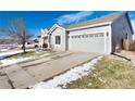 Gray house with a two-car garage and driveway, partially covered in snow at 3564 S Jebel Cir, Aurora, CO 80013