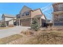 Charming two-story home featuring a stone and tan siding exterior with a three car garage and well-maintained lawn at 6472 N Dunkirk Ct, Aurora, CO 80019