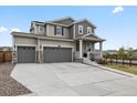 Exterior view of a two-story home with three-car garage and cozy front porch with nice landscaping at 9446 Quintero St, Commerce City, CO 80022