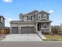 Two-story home featuring a three-car garage, charming front porch, and well-maintained landscaping at 9446 Quintero St, Commerce City, CO 80022