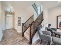 Bright foyer with hardwood floors, staircase with dark wood railing, and contemporary light fixtures, creating a welcoming entrance at 5535 W 96Th Pl, Westminster, CO 80020