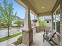 Covered front porch featuring brick columns, hanging flower baskets and comfortable seating, offering a relaxing outdoor space at 5535 W 96Th Pl, Westminster, CO 80020