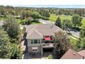 A beautiful backyard featuring a porch, stone patio and an outdoor lounge area, set amongst mature trees at 24733 E Park Crescent Dr, Aurora, CO 80016