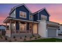 Charming two-story home featuring blue siding, white brick, covered porch, and well-manicured landscaping at 1426 Swan Peter Dr, Berthoud, CO 80513