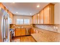 Well-lit kitchen with stainless steel appliances, granite countertops, and updated tile backsplash and flooring at 546 Lost Valley Pt, Castle Rock, CO 80108