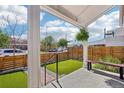 Covered front porch overlooking a fenced yard with newly installed artificial turf at 3207 N Marion St, Denver, CO 80205
