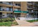 Apartment building entrance with a green awning, glass doors, a sidewalk, and some landscaping at 4801 E 9Th Ave # 402S, Denver, CO 80220