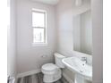 A cozy powder room featuring a modern toilet, pedestal sink, and a wall-mounted mirror at 8722 E 47Th Ave, Denver, CO 80238