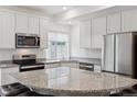 Bright kitchen featuring granite countertops, stainless steel appliances, and white cabinetry at 4028 N Rome St, Aurora, CO 80019