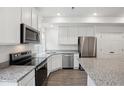 Modern kitchen with stainless steel appliances, granite countertops, and white cabinets at 4028 N Rome St, Aurora, CO 80019