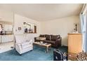 Cozy living room featuring a plush leather sofa, comfortable armchair, and an open pass-through to the kitchen at 2108 S Idalia S St, Aurora, CO 80013