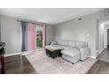 Living room featuring a gray sectional, wood floors, and sliding glass doors leading to the outside at 10211 Ura Ln # 8-102, Thornton, CO 80260