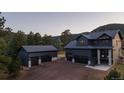 Beautiful dark modern home with a detached garage in a serene setting surrounded by lush greenery and distant mountains at 30796 Burland Rd, Golden, CO 80403