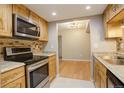Kitchen featuring stainless steel appliances, wood cabinets, and a view of the adjacent dining area at 3550 S Harlan St # 259, Denver, CO 80235