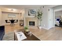 Bright living room with a tiled fireplace, dining area, modern lighting, and wood-look flooring at 3550 S Harlan St # 259, Denver, CO 80235