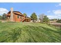 Spacious backyard featuring a wooden deck and balcony, lush green lawn, and a wooden fence at 8072 Windwood Way, Parker, CO 80134