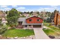 Beautiful two-story home with a lush green lawn, mature trees, and an attached two car garage and long driveway at 8072 Windwood Way, Parker, CO 80134