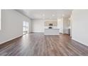 An open living room area with hardwood floors, a modern kitchen, and natural light at 2169 Flower Blossom Ave, Brighton, CO 80601