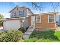 Two-story home with neutral siding, brick accents, two-car garage, and steps leading to the entrance at 3732 S Halifax St, Aurora, CO 80013