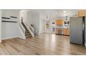 Bright living room with wood floors, white walls, stairs, and an open floor plan to the kitchen at 3732 S Halifax St, Aurora, CO 80013