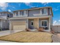 Two-story gray home with a beige two car garage and a partially dormant lawn on a bright sunny day at 5251 Truckee St, Denver, CO 80249