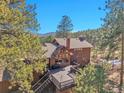 Aerial rear exterior view of home displaying spacious deck and sunroom surrounded by mature pine trees at 29571 Dorothy Rd, Evergreen, CO 80439