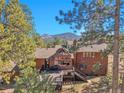 Rear exterior of home showcasing an expansive deck and sunroom addition with large windows, surrounded by trees and mountains at 29571 Dorothy Rd, Evergreen, CO 80439
