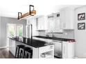 Modern kitchen features white cabinets, stainless steel appliances, a stylish island with black countertops, and contemporary lighting fixtures at 11354 Allendale Dr, Arvada, CO 80004