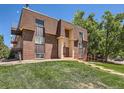 Brick apartment building with well-kept landscaping, mature trees, and direct access to the unit at 7755 E Quincy Ave # 301A7, Denver, CO 80237