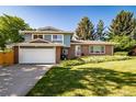 Beautiful two-story brick home with a well-manicured lawn and mature trees, showcasing curb appeal and a two car garage at 5404 W Rowland Pl, Littleton, CO 80128