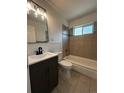 Well-lit bathroom featuring a modern vanity, tiled floors, and tiled shower-tub combination at 1550 Eppinger Blvd, Thornton, CO 80229
