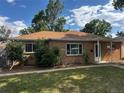 Charming brick home with a well-manicured lawn, mature trees, and beautiful landscaping at 1550 Eppinger Blvd, Thornton, CO 80229