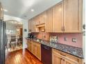 Well-lit kitchen featuring wooden cabinets, granite countertops, stainless steel appliances, and hardwood floors at 3002 E Long S Cir, Centennial, CO 80122