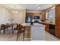 Well-lit kitchen features a breakfast bar, wood cabinetry, and black appliances next to a dining area at 9461 Ashbury Cir # 104, Parker, CO 80134