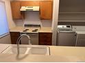 Kitchen featuring stove, overhead vent, and a view of washer and dryer units at 10650 E Tennessee Ave # 101, Aurora, CO 80012