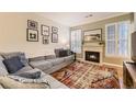 Cozy living room featuring a fireplace, plush sectional, and bright windows with shutter-style blinds at 7418 S Quail Cir, Littleton, CO 80127
