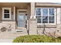 Charming covered front porch with brick pillars, seating, and an inviting front door with decorative glass at 10843 W Hinsdale Dr, Littleton, CO 80127