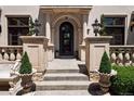 Elegant front entrance featuring a decorative iron door, stone columns, and manicured landscaping at 9171 E Harvard Ave, Denver, CO 80231